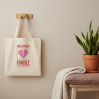 Stoffbeutel Fragile mit gebrochenem Herz Design hängt an Wand neben Textilien und Pflanze