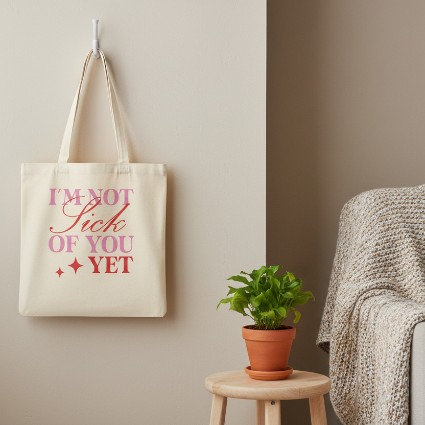 Stoffbeutel I'm not sick of you yet mit rosa und rotem Text hängt an Wand neben Strickdecke