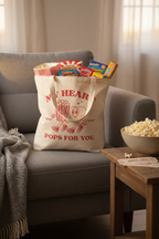 Baumwollbeutel My heart pops for you gefüllt auf grauem Sofa mit Popcorn und Kinokarten