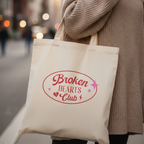 Frau trägt Statement Stoffbeutel Broken Hearts Club in beigem Oversized Pullover